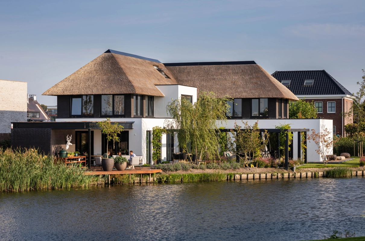 Een kubistisch landelijke villa met rieten dak met zicht op het water
