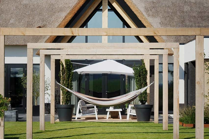 Achterzijde landelijke villa met pergola's en hangmat in de tuin