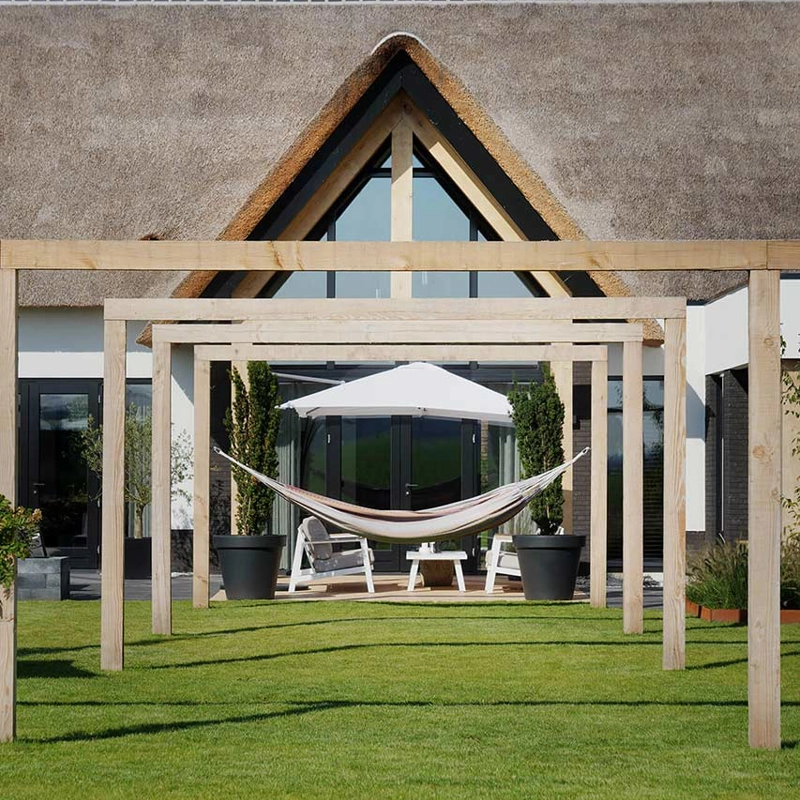 Achterzijde landelijke villa met pergola's en hangmat in de tuin