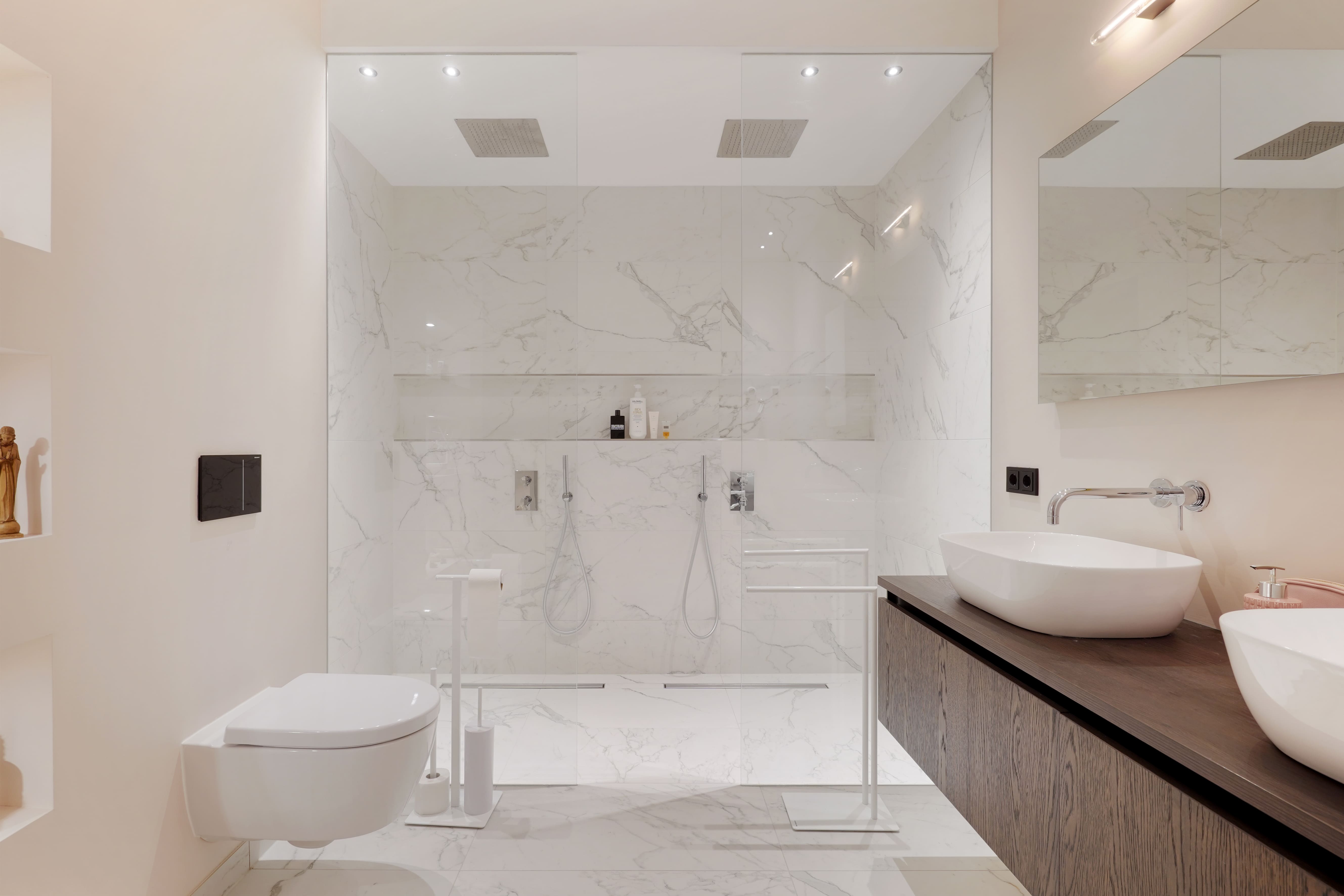Een badkamer met witte marmeren wandtegels en inloopdouche