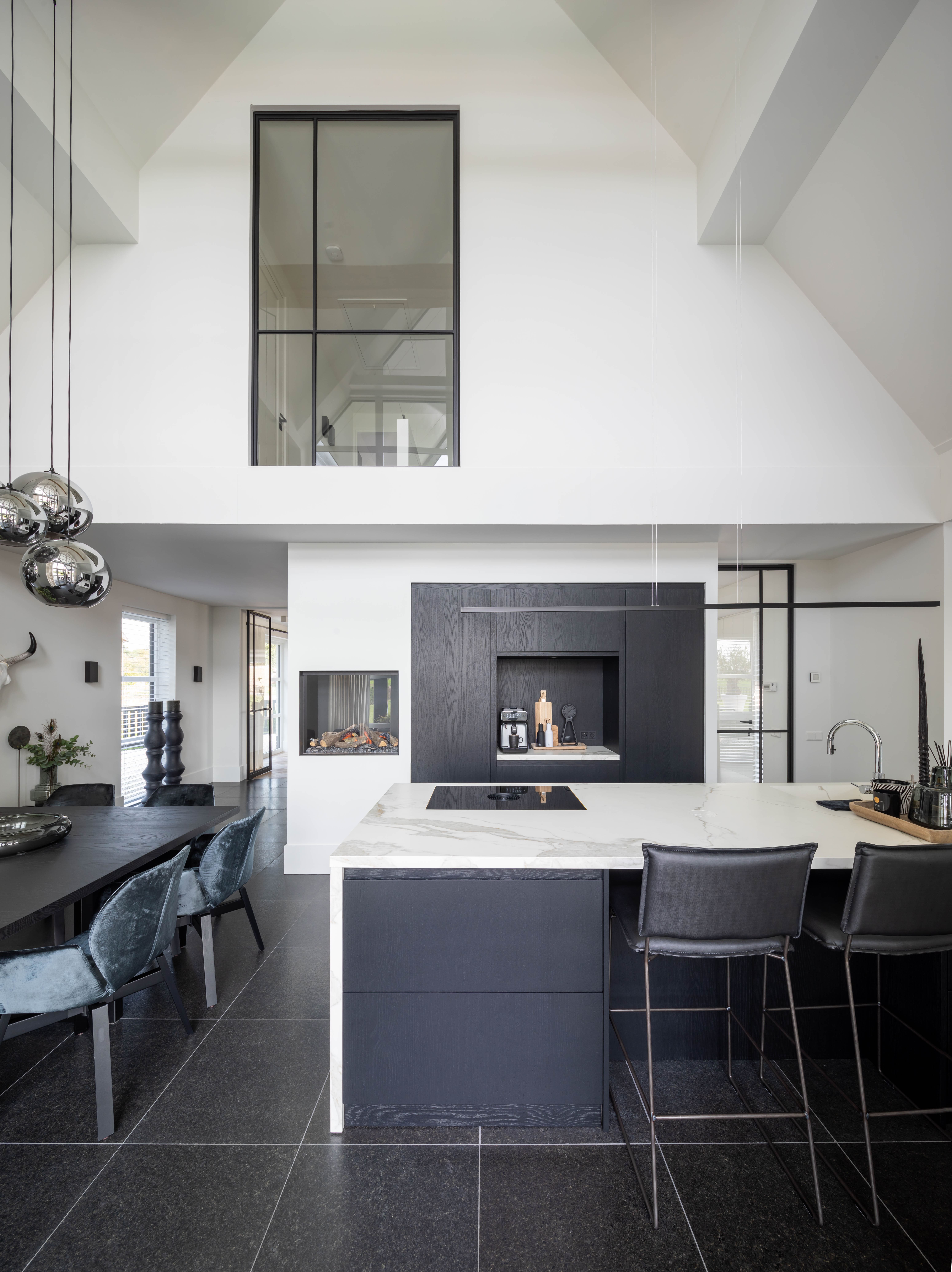 luxe designkeuken met zwarte afwerking en witte marmeren keukenblad
