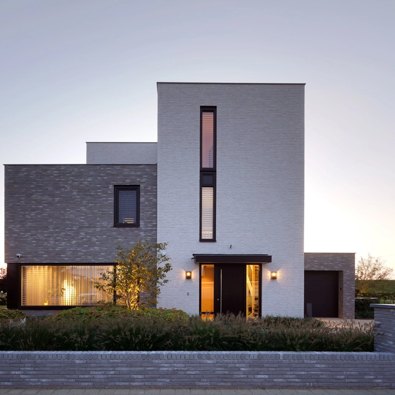 De voorgevel van een moderne, kubistische villa met wit en grijze gevelafwerking