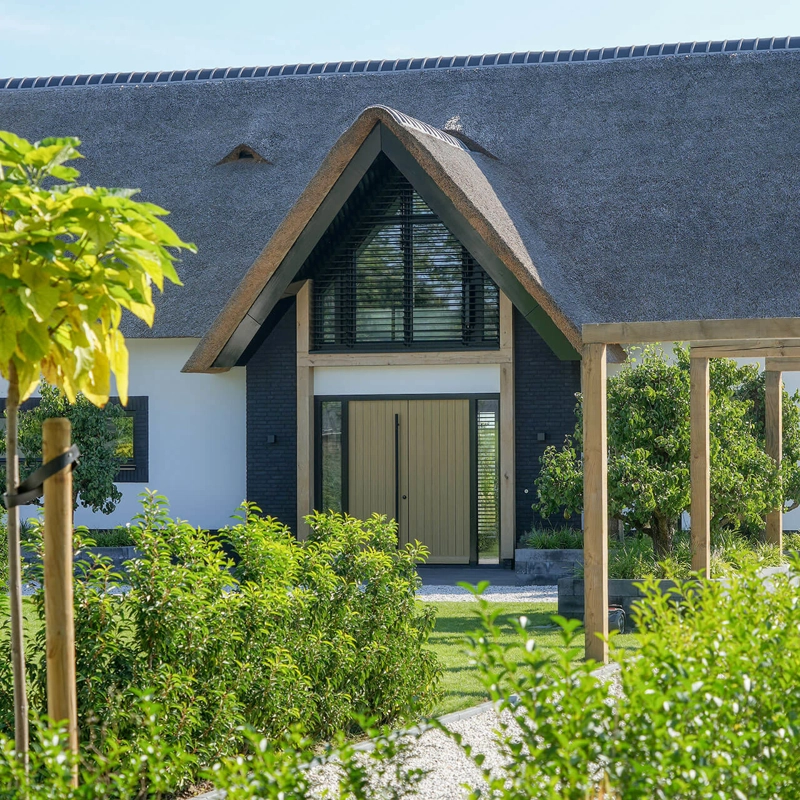 Voorzijde van een landelijke villa met rieten kap en houten spanten