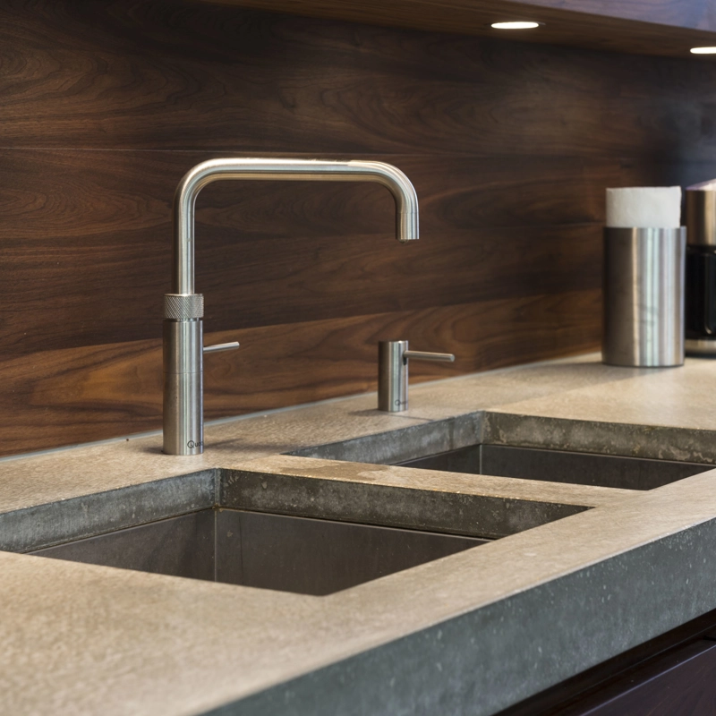 Een betonlook aanrechtblad met dubbele wasbak en designkraan