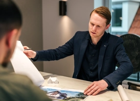Architect voert adviesgesprek met klant terwijl hij in brochure bladert