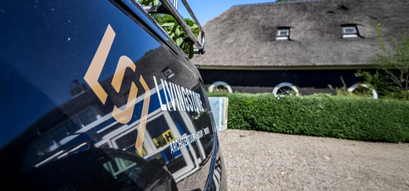 Close up van een Livingstone bus met een woonboerderij op de achtergrond