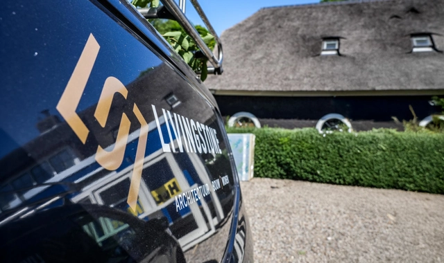 Close up van een Livingstone bus met een woonboerderij op de achtergrond