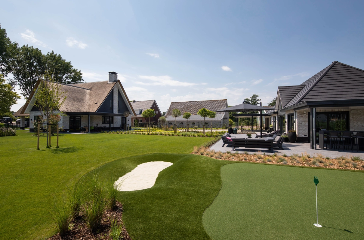 Een golfbaan in de achtertuin van een landelijke villa met rieten kap