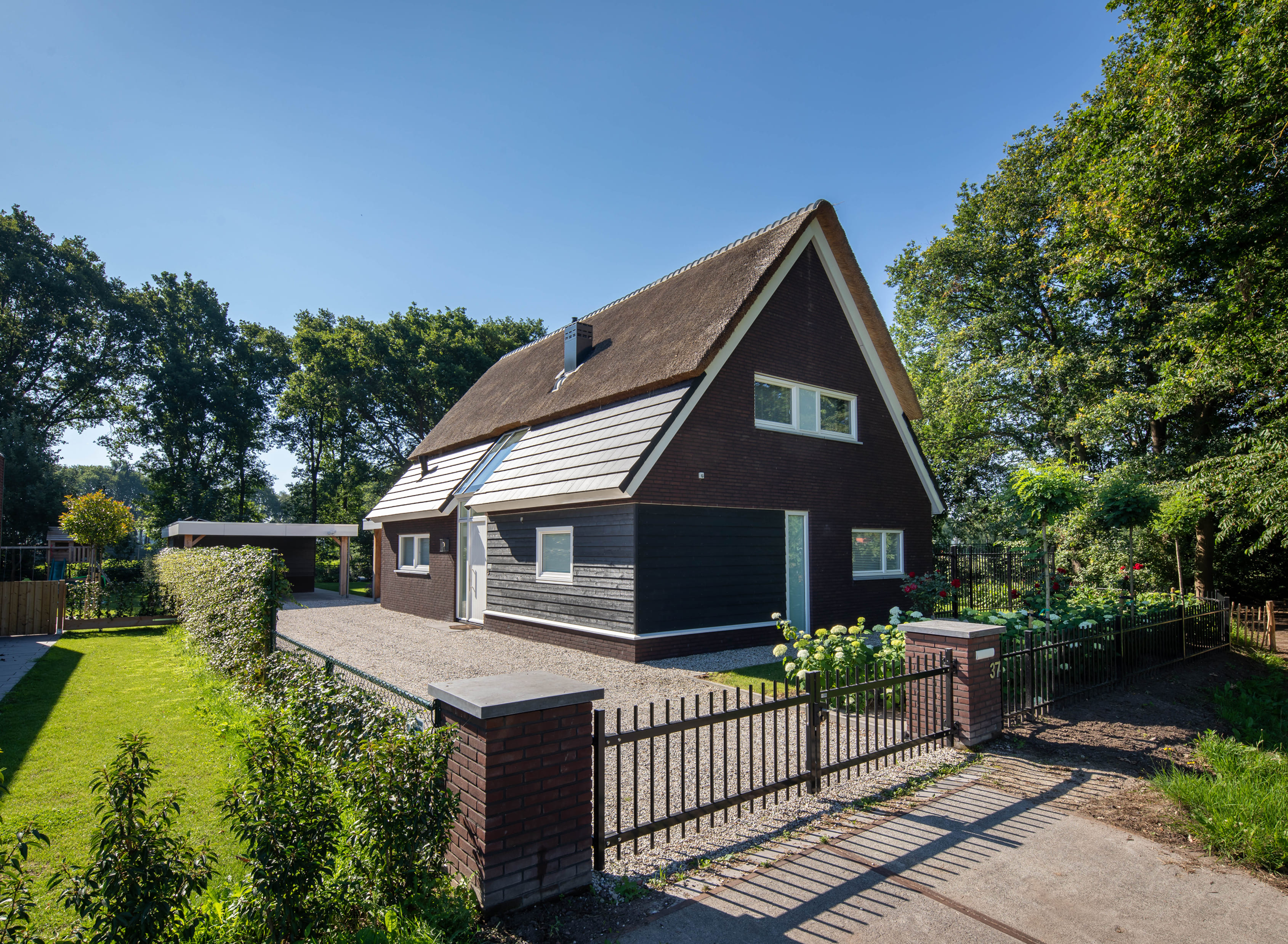 Boerderijwoning met rieten dak en donkere gevelbekleding