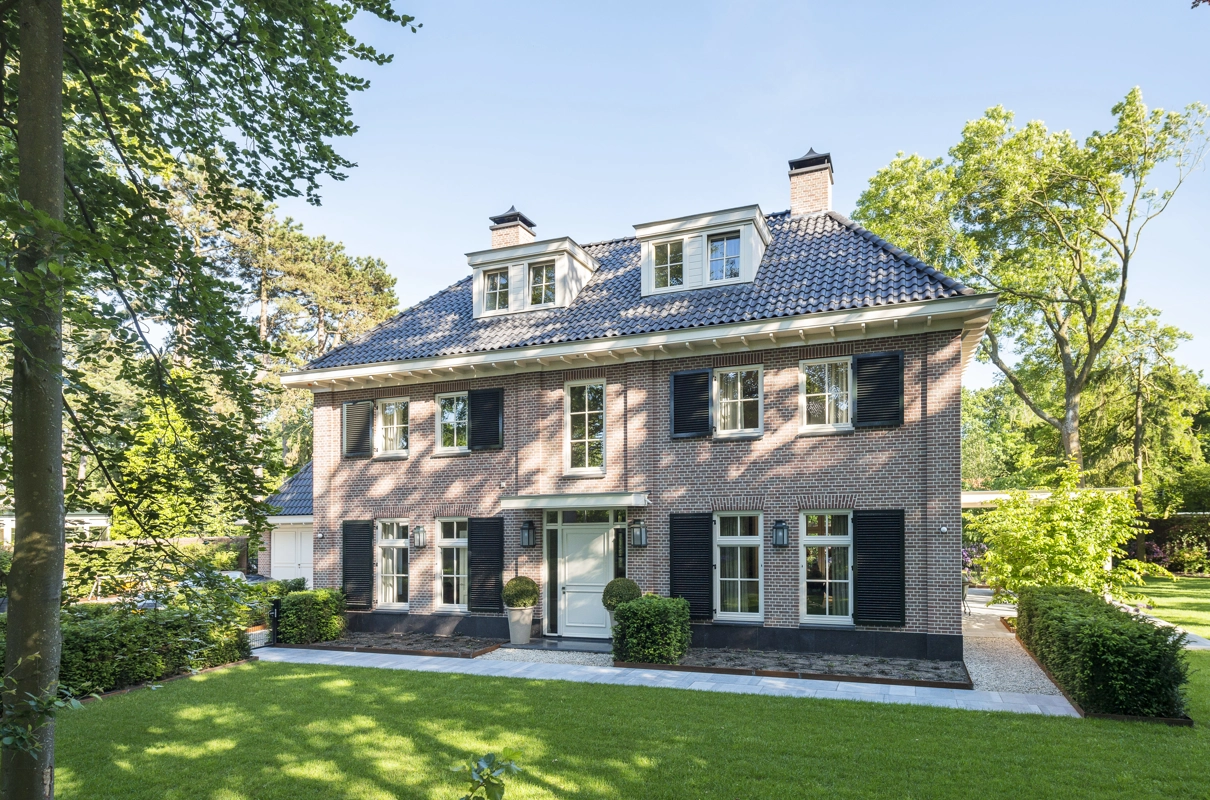Het vooraanzicht van een notariswoning met rode bakstenen en dakkapel