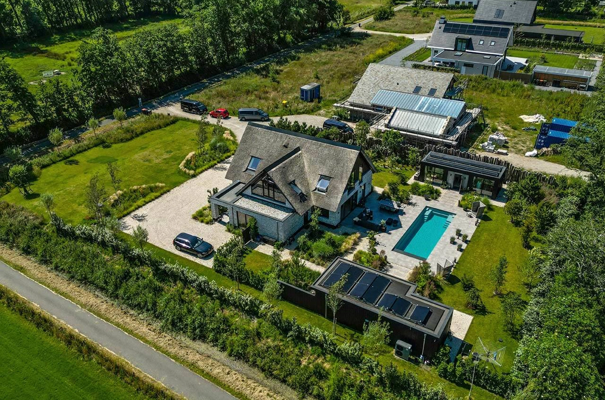 Bovenaanzicht van landelijke villa met rieten dak, groot perceel en buitenzwembad