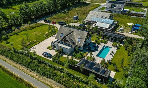 Bovenaanzicht van landelijke villa met rieten dak, groot perceel en buitenzwembad