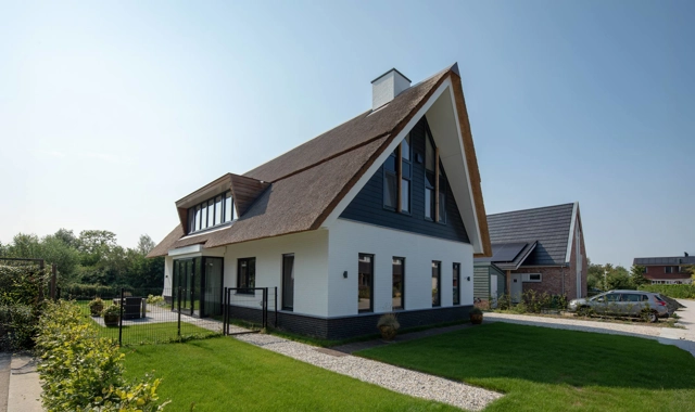 Boerderijwoning met wit zwarte gevel en rieten dak