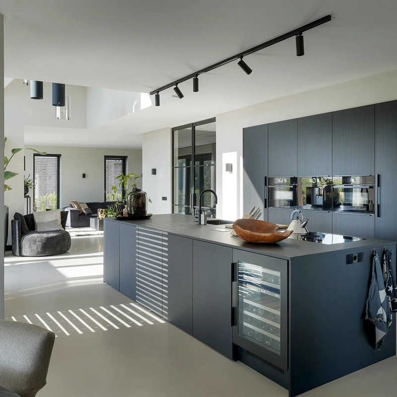 Een luxe, zwarte designkeuken met grijze gietvloer