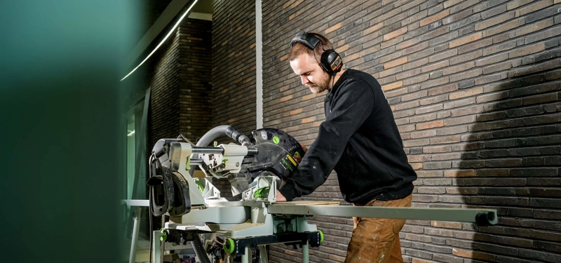 Een uitvoerder zaagt een aluminium profiel
