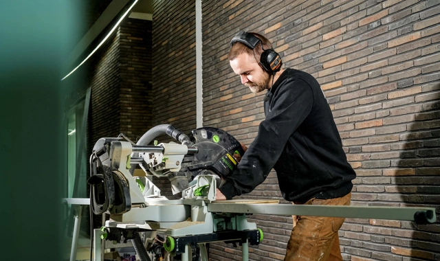 Een uitvoerder zaagt een aluminium profiel