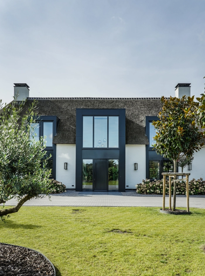 Voorzijde van villa met rieten dak en gras