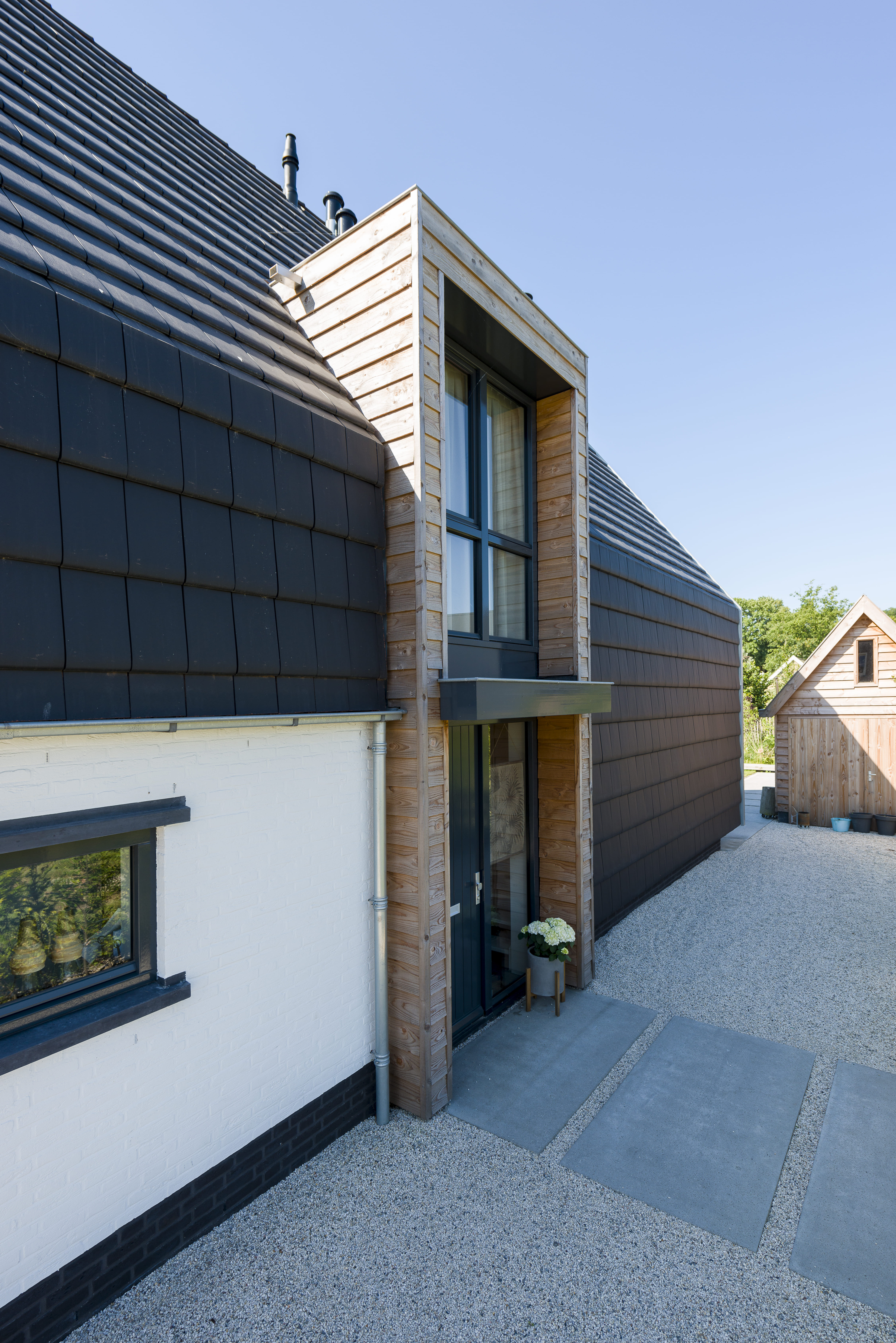 Voorzijde van een jaren 70 woning met witte gevelbekleding