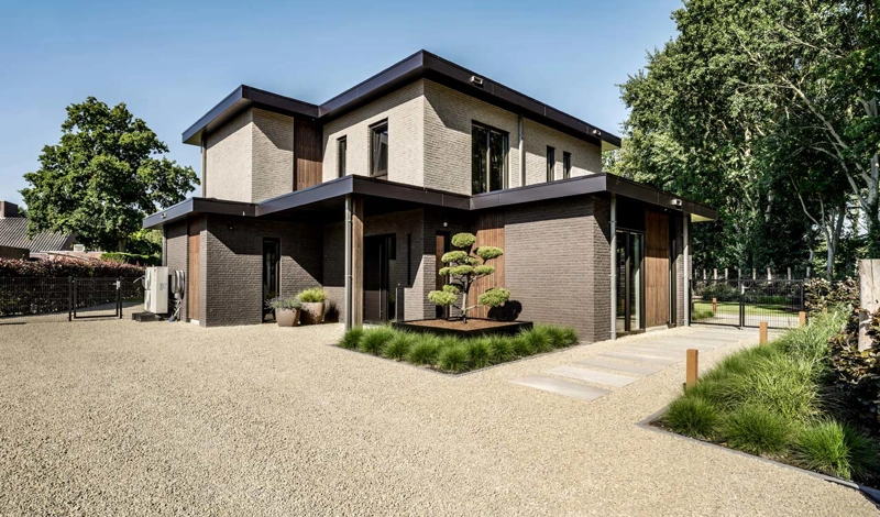 Entree moderne villa met boom en oprijlaan