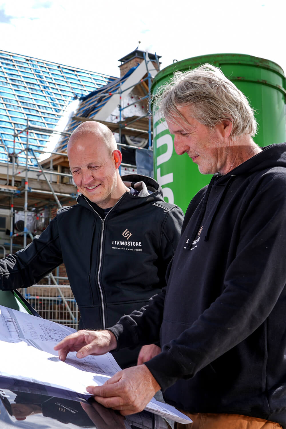 Een uitvoerder en projectleider aan het overleggen op de bouwplaats
