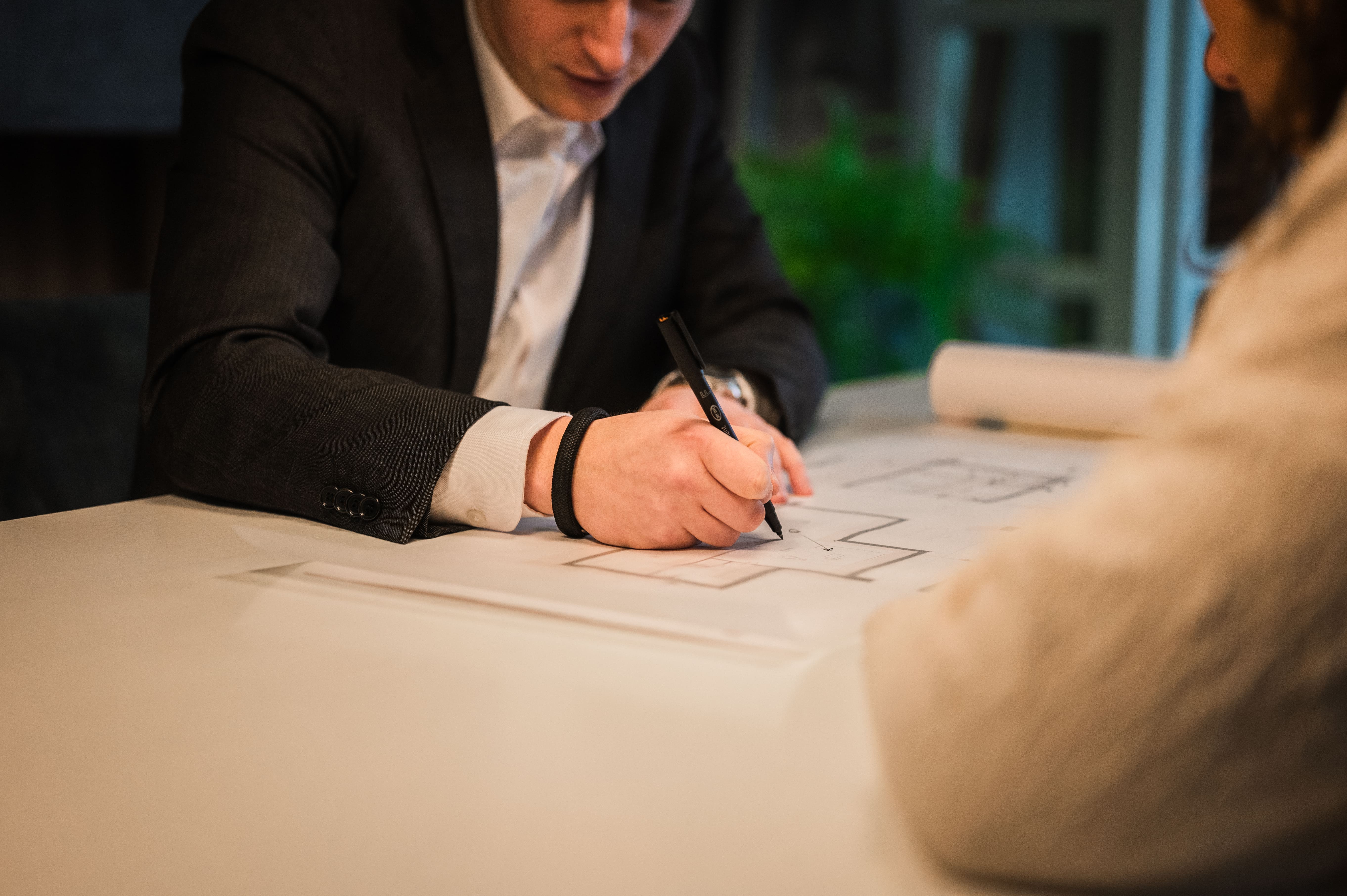 Architect schets een ontwerp en is in gesprek met klanten 