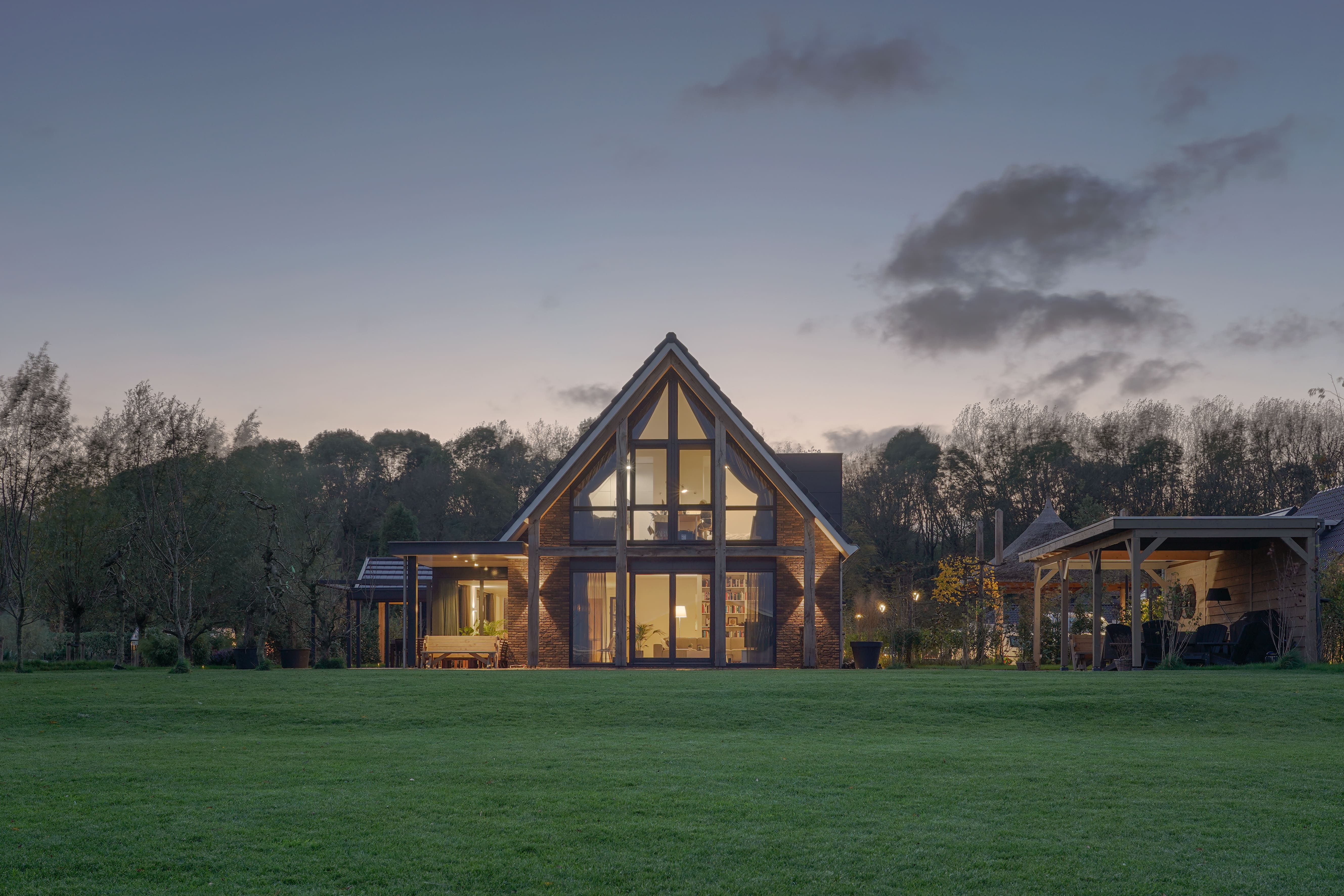 Moderne schuurwoning met glaspui en sfeerverlichting in de avond gefotografeerd