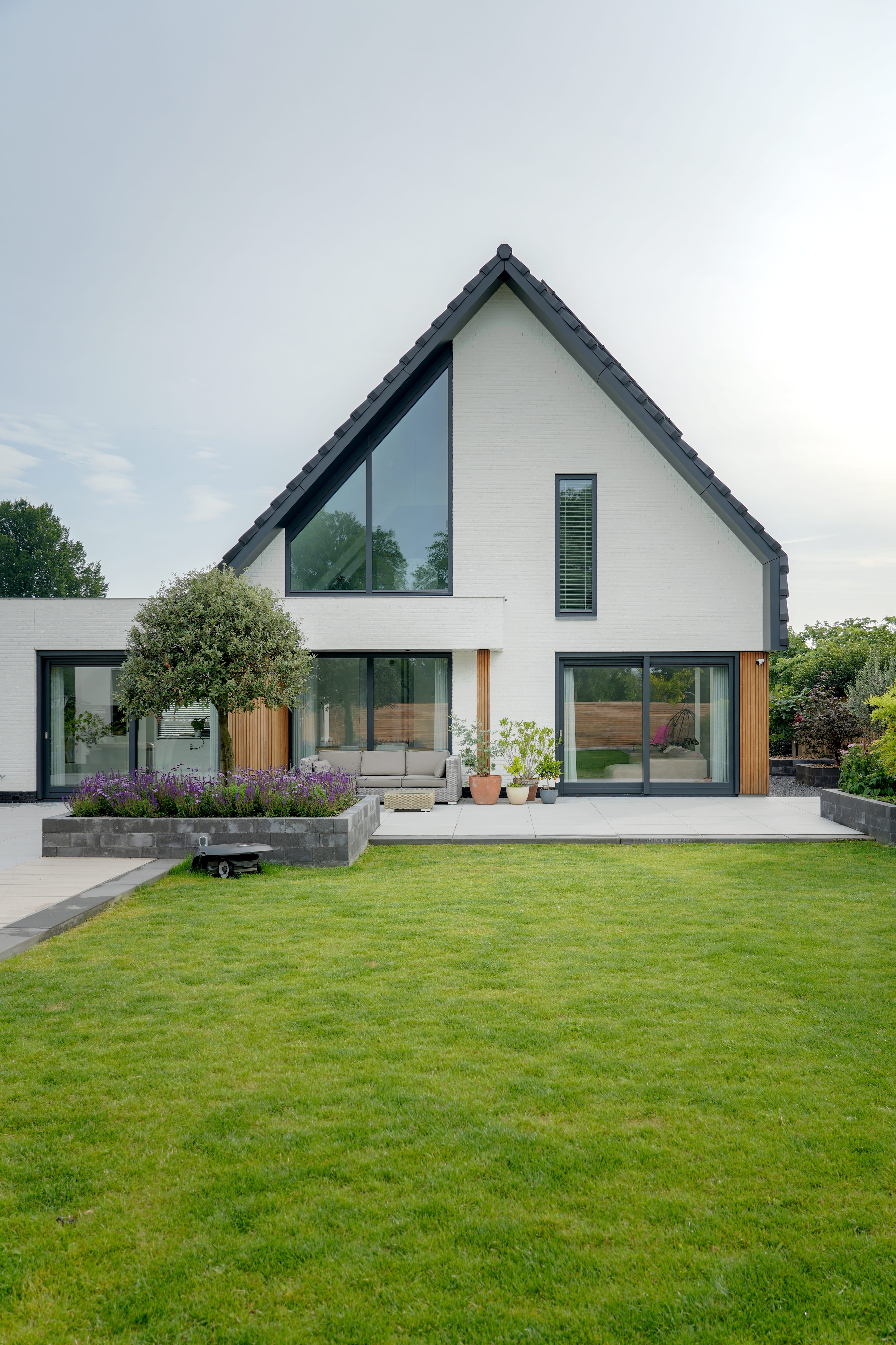 Moderne schuurwoning met witte gevel en groen grasveld