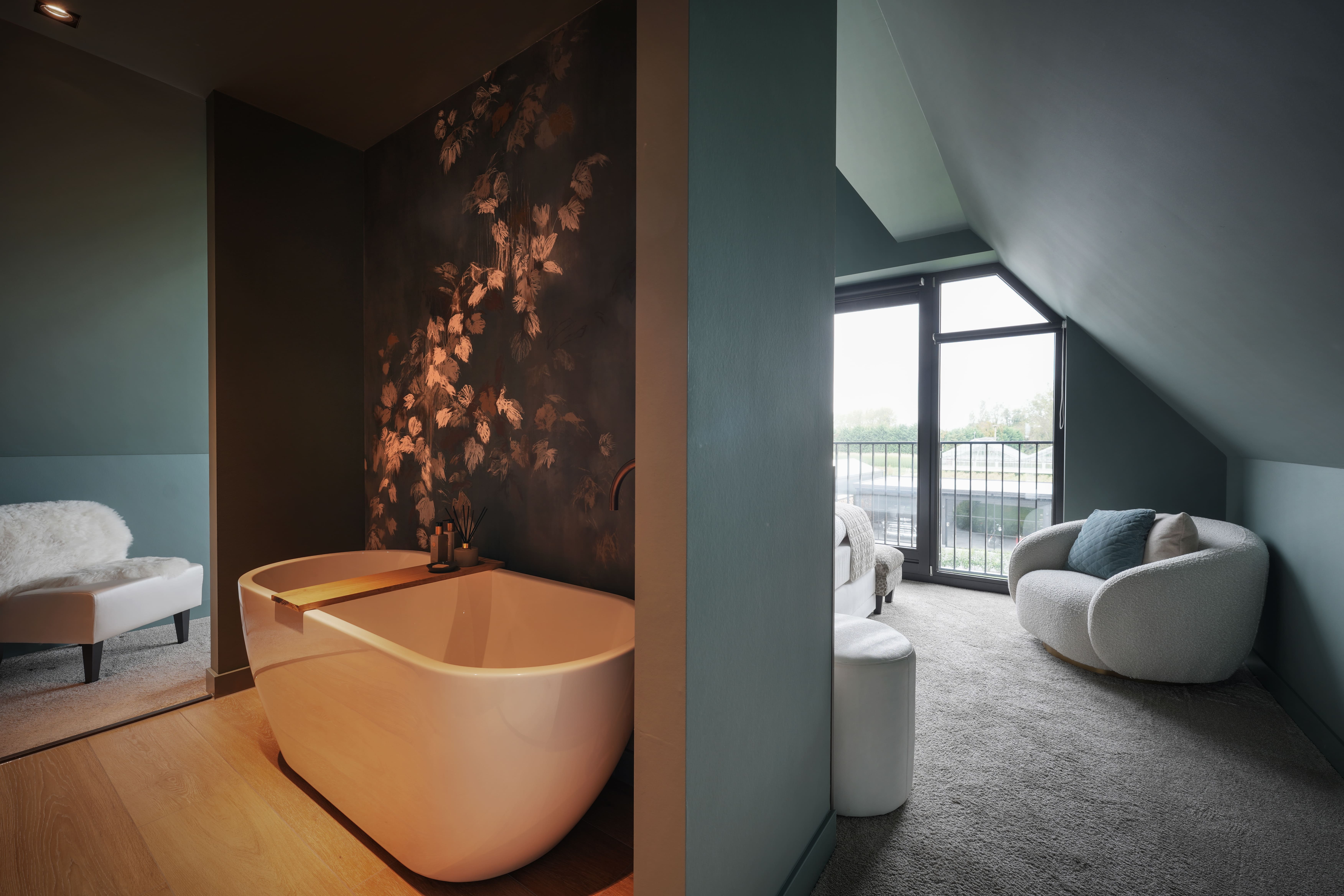 Badkamer en suite met ligbad en donkere muurbekleding