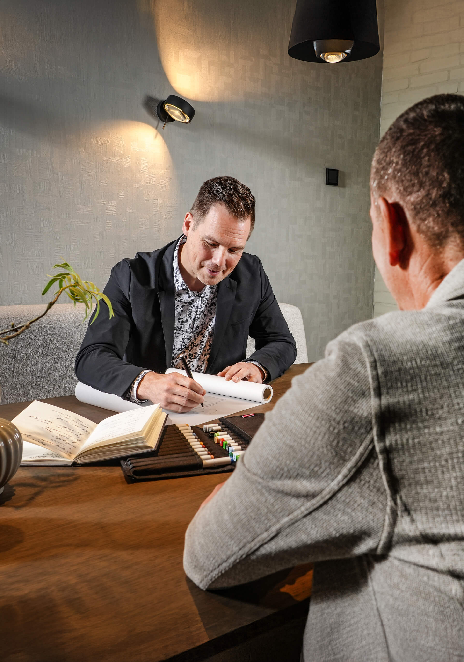 Architect schets een ontwerp en is in gesprek met een klant