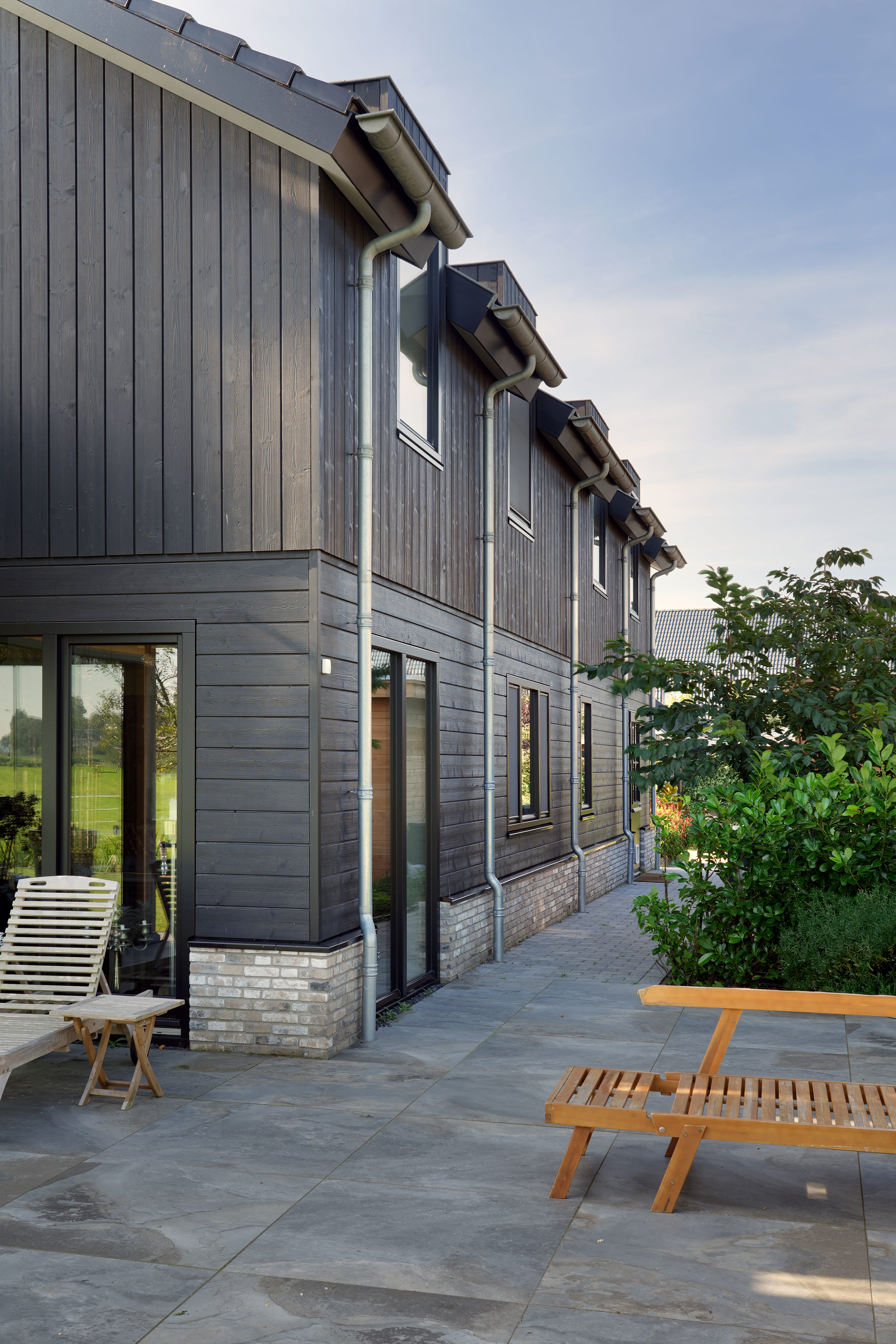 Zijaanzicht van een moderne schuurwoning met zwarte gevelbekleding