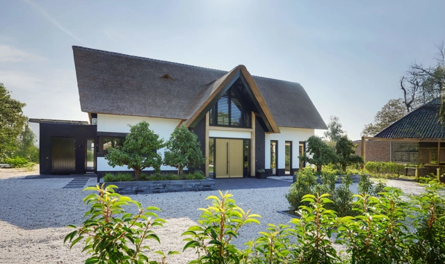 Voorzijde van een landelijke villa met rieten kap en houten spanten