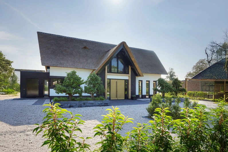 Voorzijde van een landelijke villa met rieten kap en houten spanten