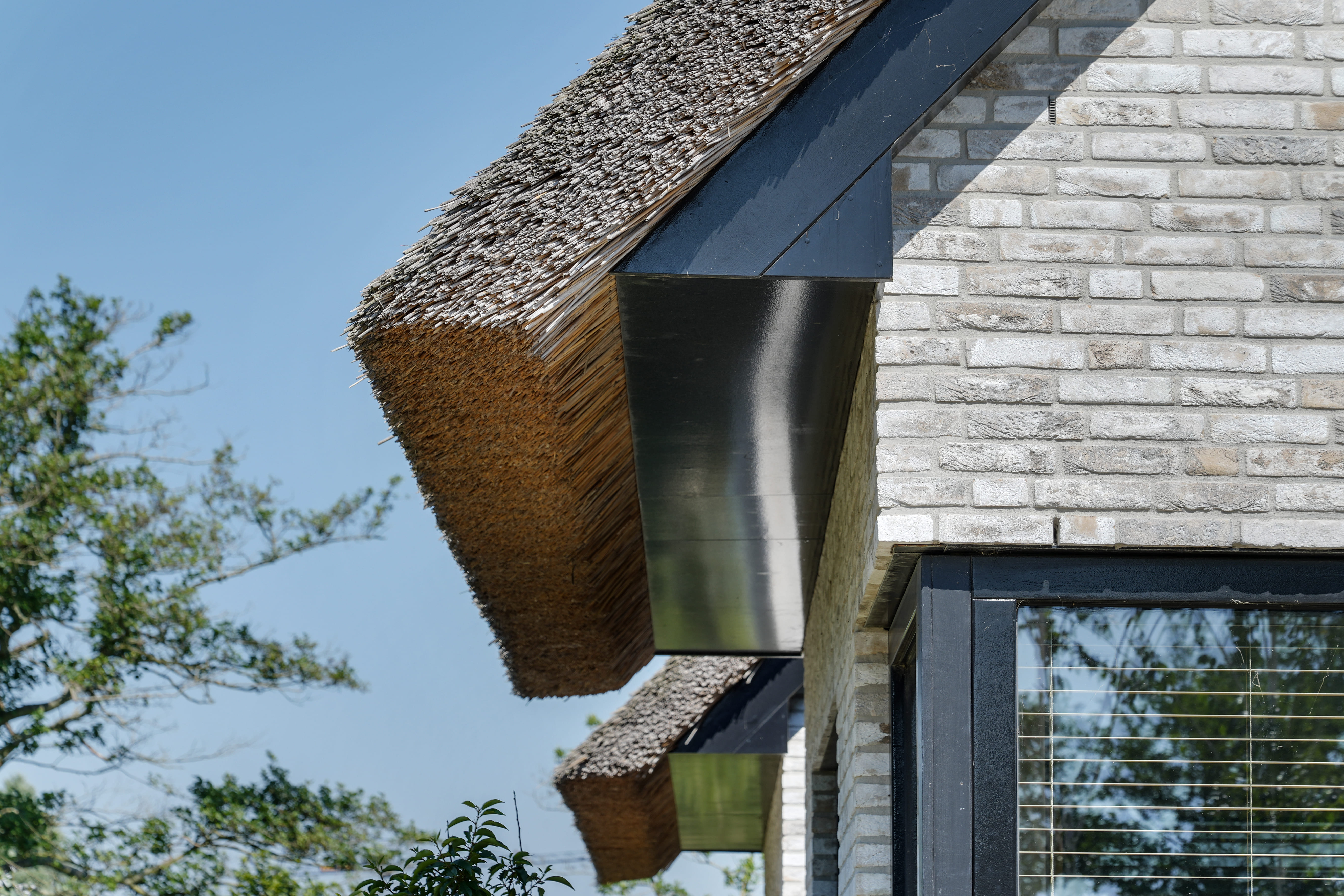 Uitsnede grijze gevel en rieten dak